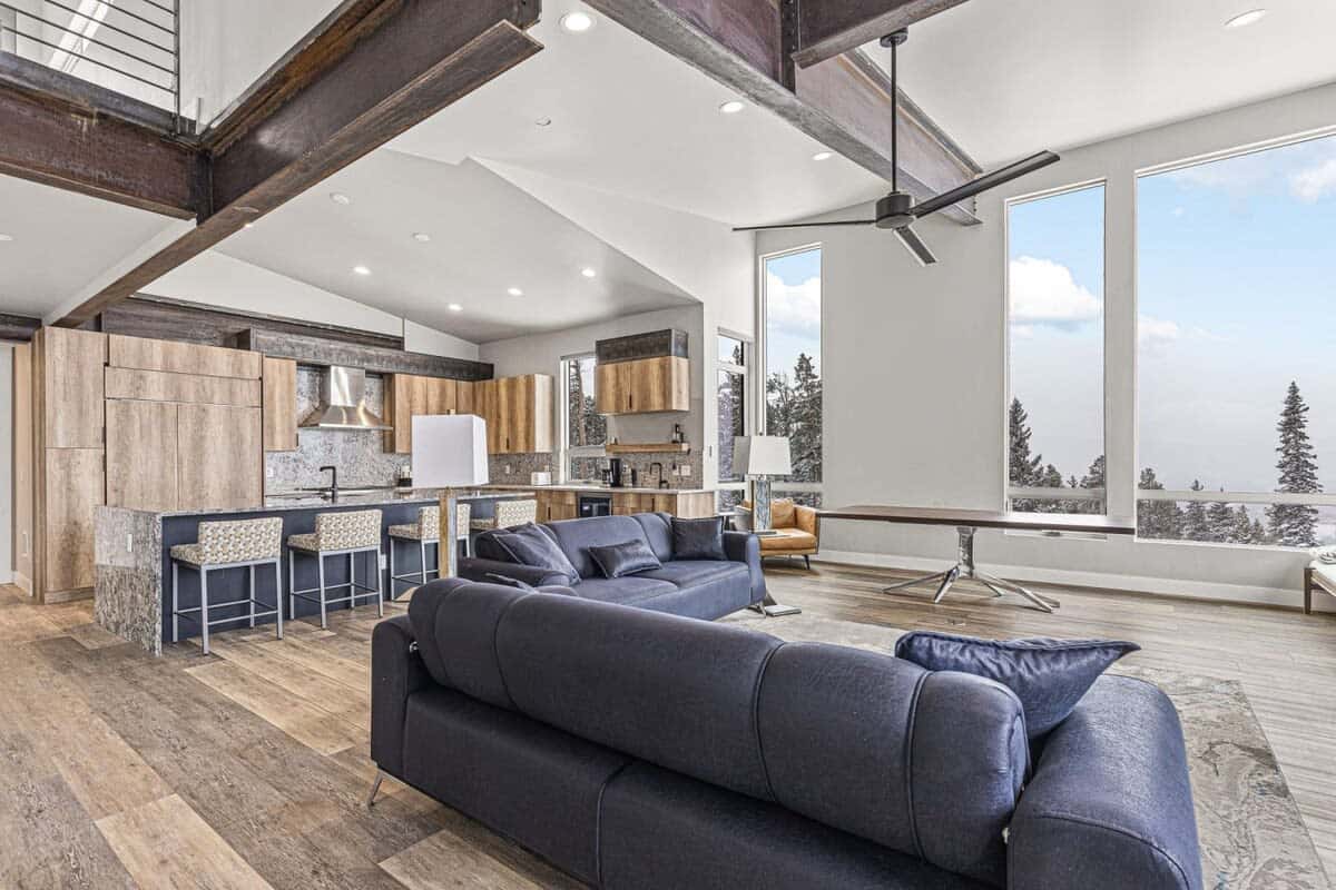 Relax in this modern and spacious family room with luxurious sofa seating, a built-in fireplace, a flat-screen TV, and expansive floor-to-ceiling windows throughout the space